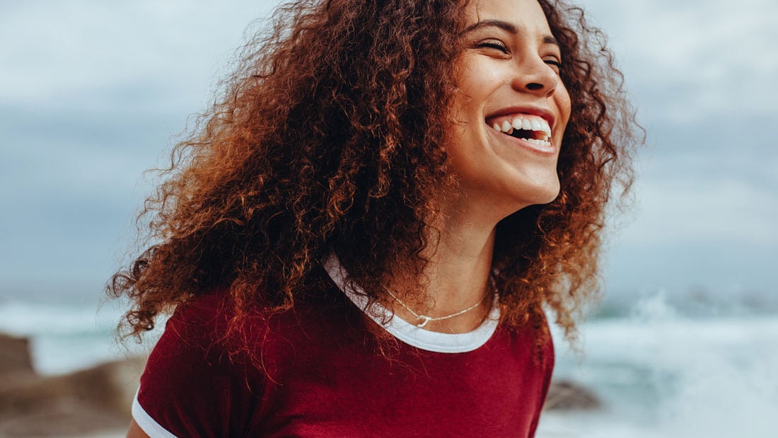 Happy woman with curly hair - Health WakeUp